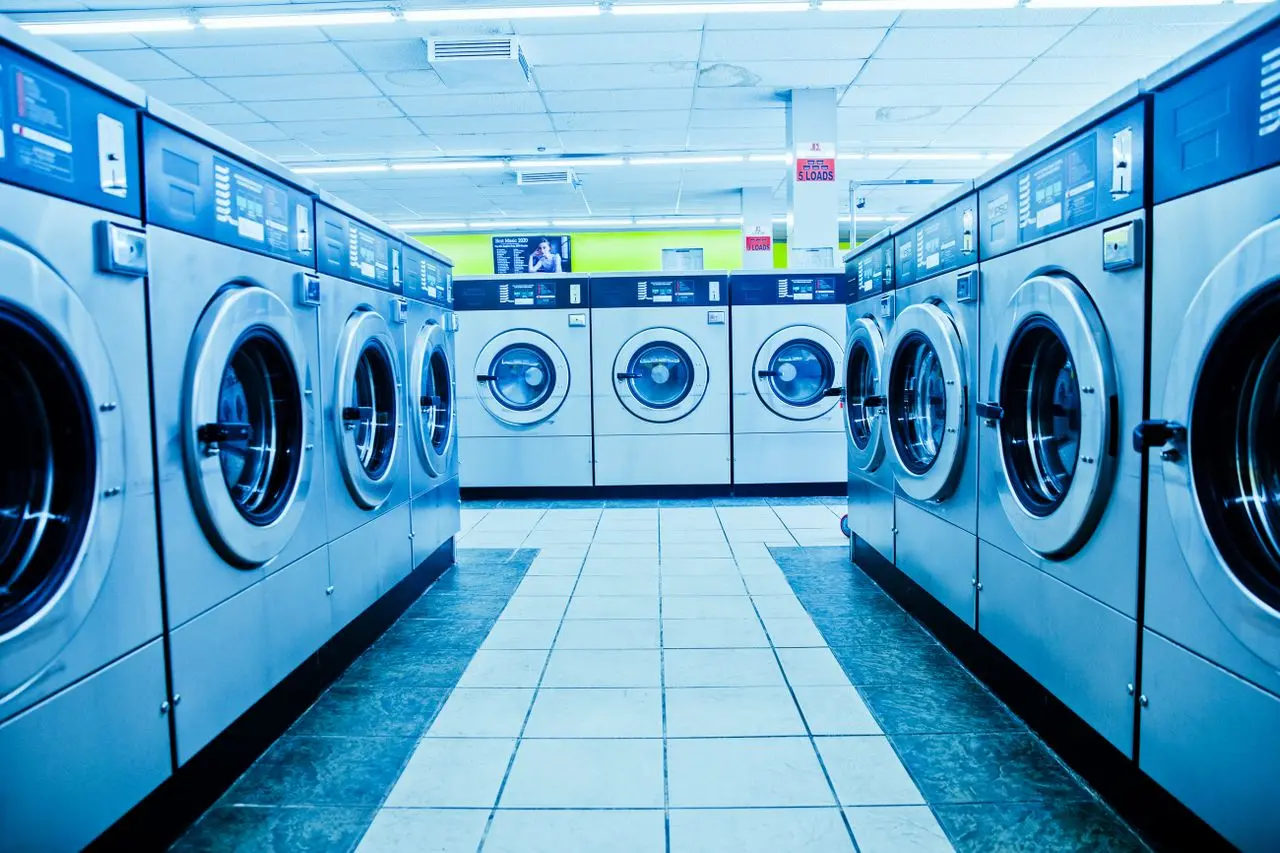 Lavanderia autônoma com fileiras de máquinas de lavar e secar roupas.