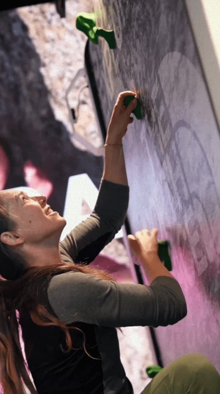 Bride sitting on ground against wall, groom standing nearby