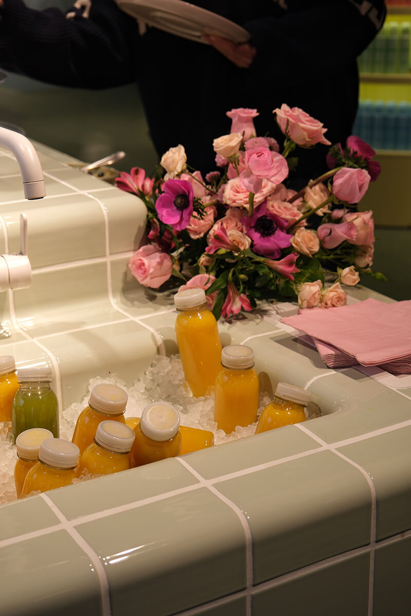 Orange juice bottles placed on ice and a bunch of flowers placed next to it