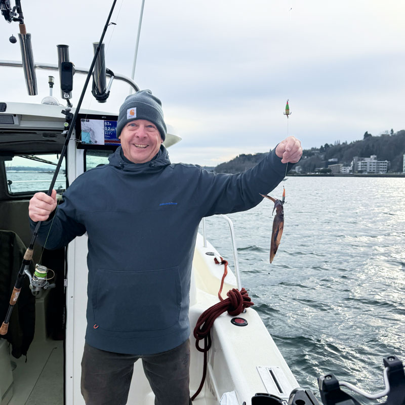 Man on a boat reeling a squid