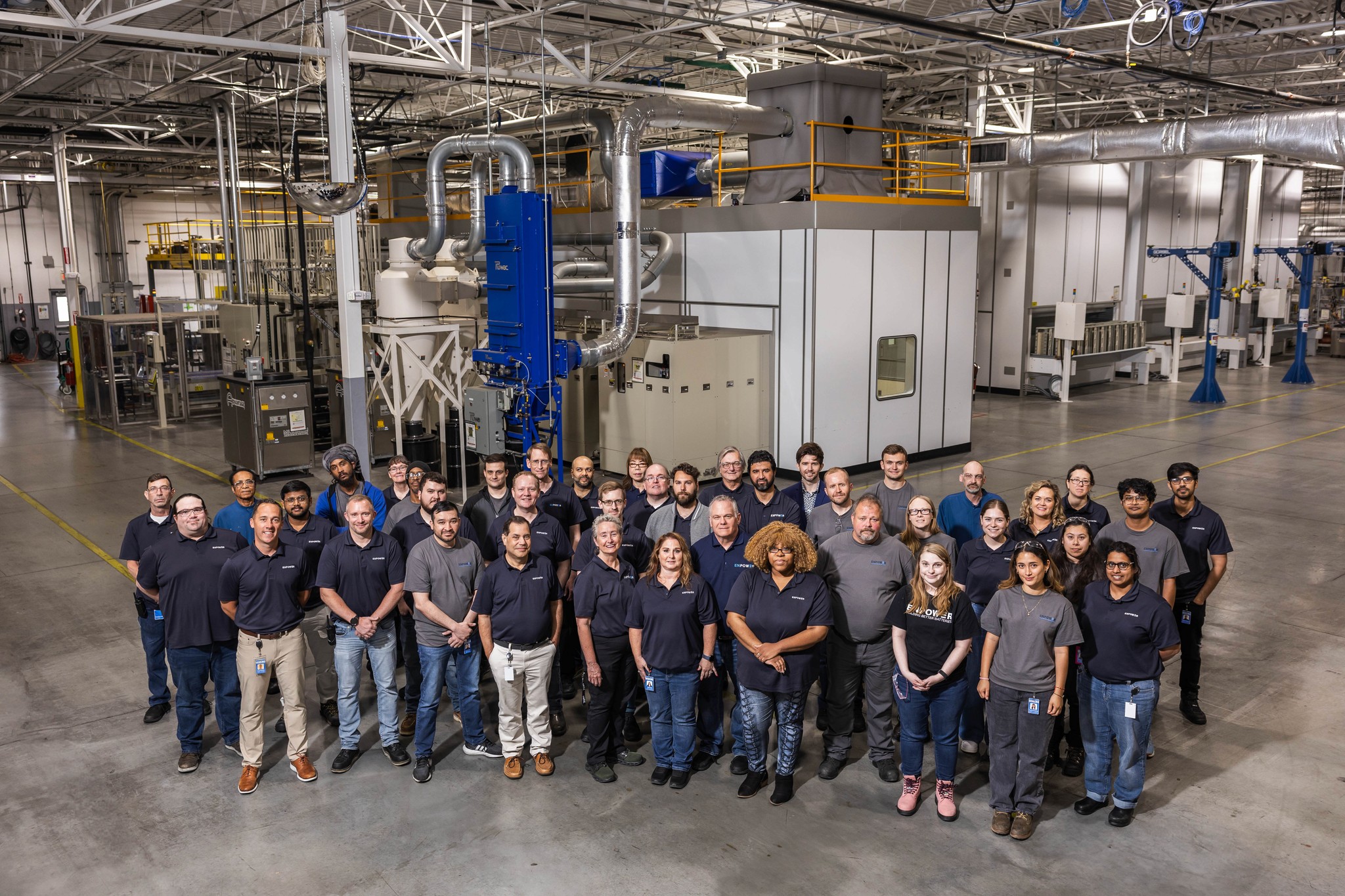 Photo of the EnPower team at the EnPower HQ building with equipment in the background