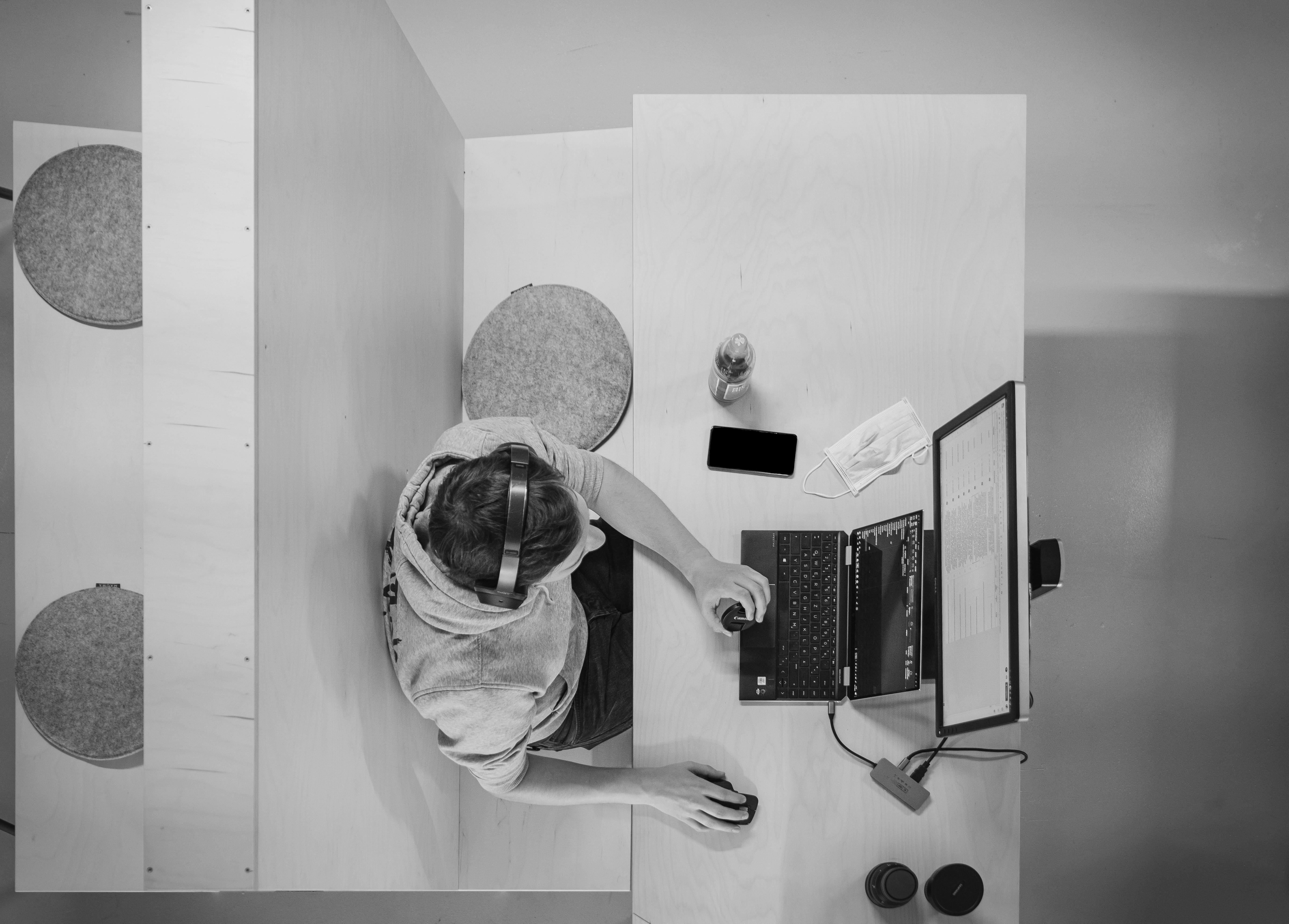 Aerial view of a child sitting at a table, focused on a small stove or kitchen appliance. Black and white image.