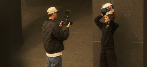 Person filmt eine andere Person mit Helm vor dunklem Hintergrund. Fotosession oder hinter den Kulissen.