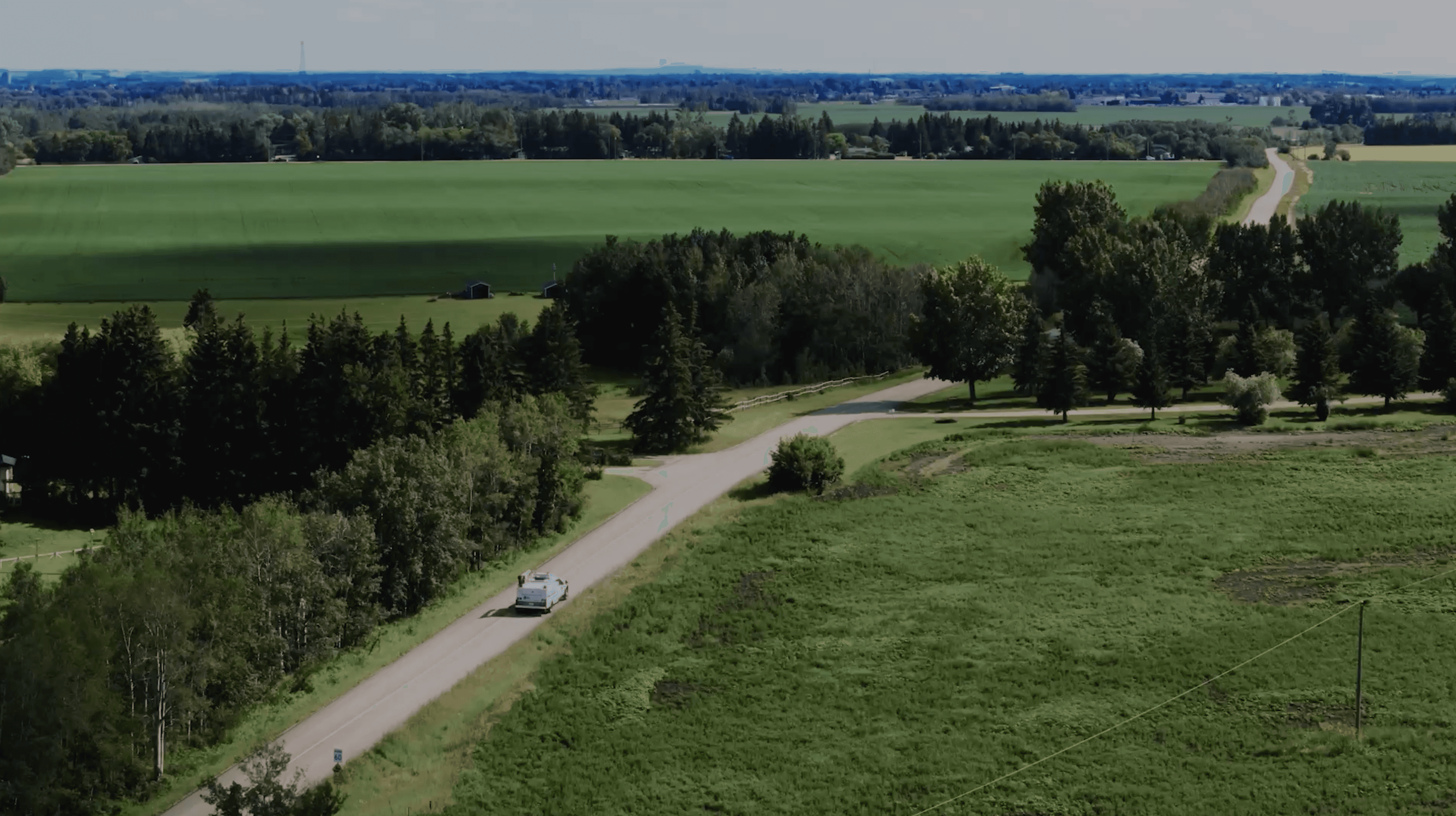 Close-up portrait of a person wearing a gray insulated hooded jacket with the hood up, showing their face framed by the hood against a light background.