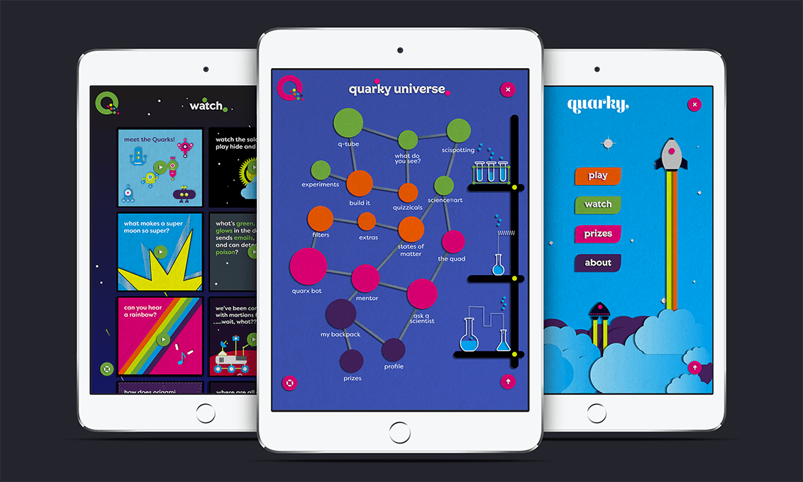 Three tablets display different apps. The leftmost tablet shows a colorful interface with text and graphics, including “watch,” “meet the Quarks!,” “what makes a super moon so super?,” and “how does a rainbow?” The center tablet displays a colorful diagram with circles and text, labeled “quarky universe,” including terms like “quark,” “states of matter,” and “science=art.” The rightmost tablet shows a rocket-themed app with buttons labeled “play,” “watch,” “prizes,” and “about,” set against a blue background with clouds and a rocket.