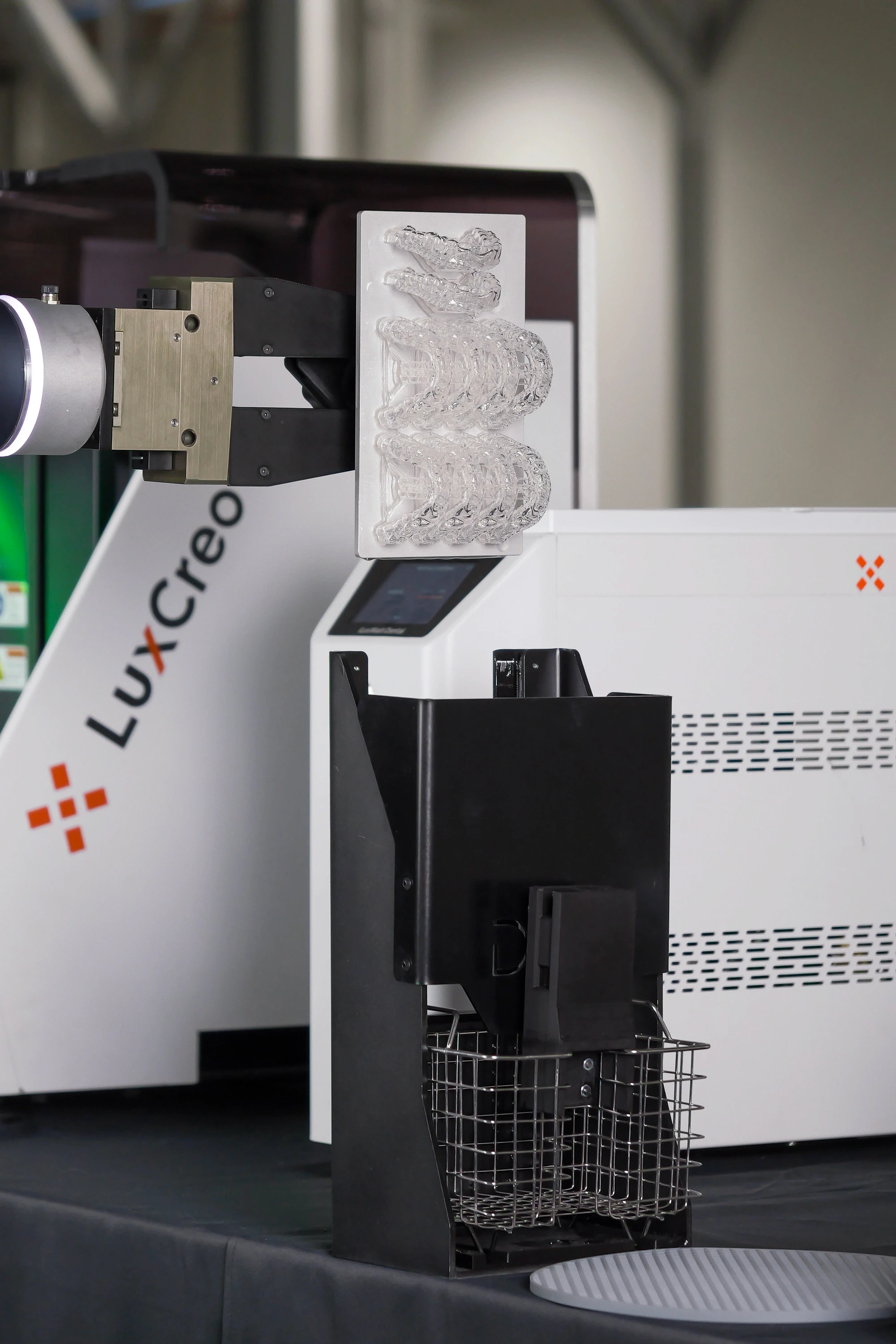 Robotic arm automatically scraping direct-print clear aligners into a custom wash basket, eliminating manual harvesting.
