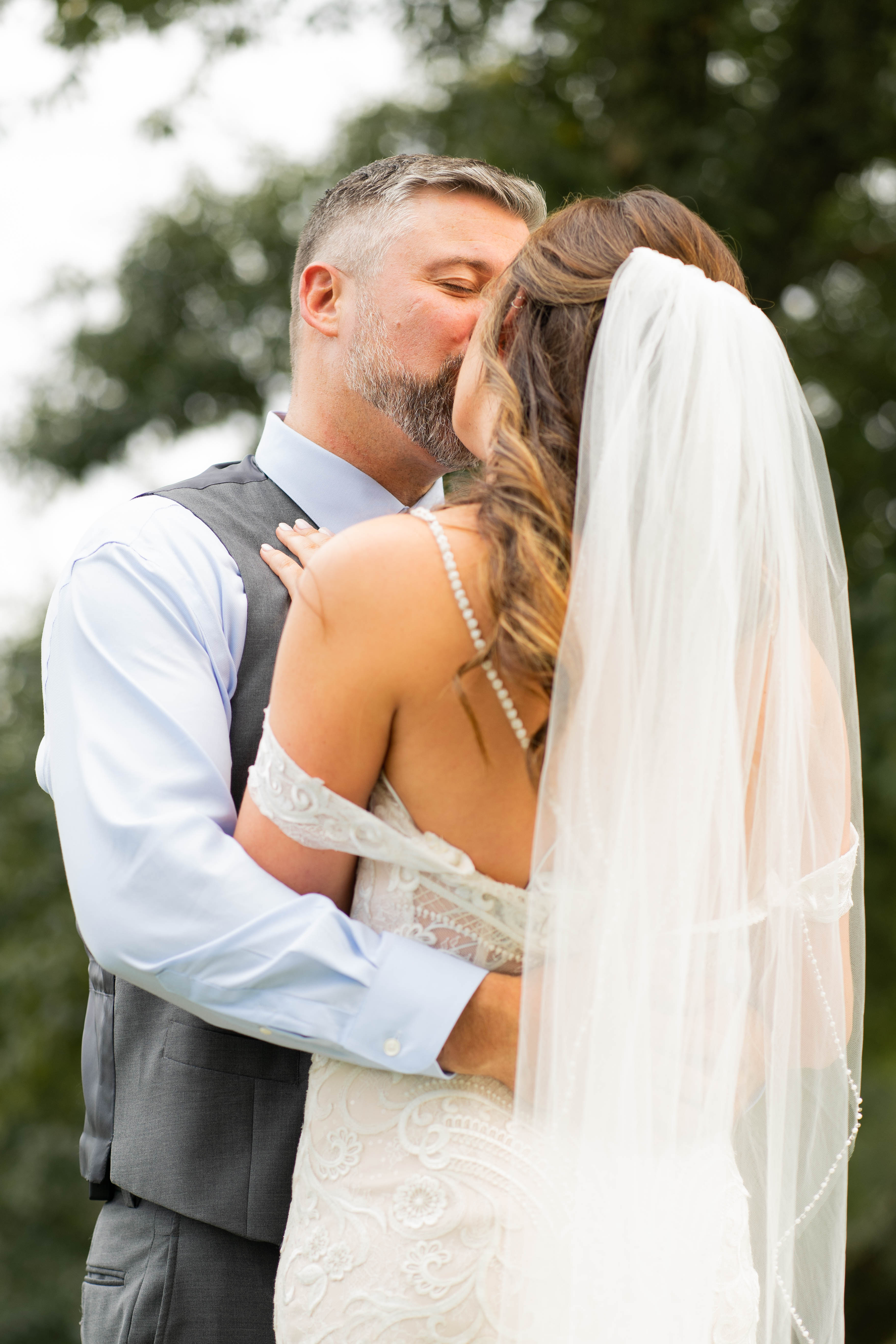 A bride and groom share a kiss surrounded by a joyful bridal party.