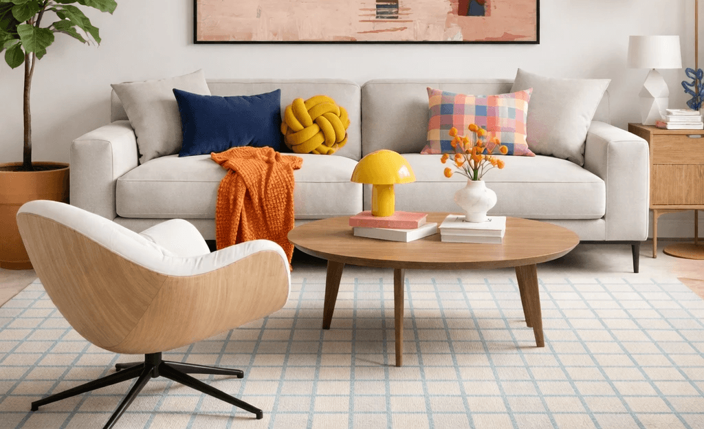 Scandinavian modern apartment living room with oversized abstract wall art, neutral sofa, oak chair, blue and rust accents, and grid area rug.