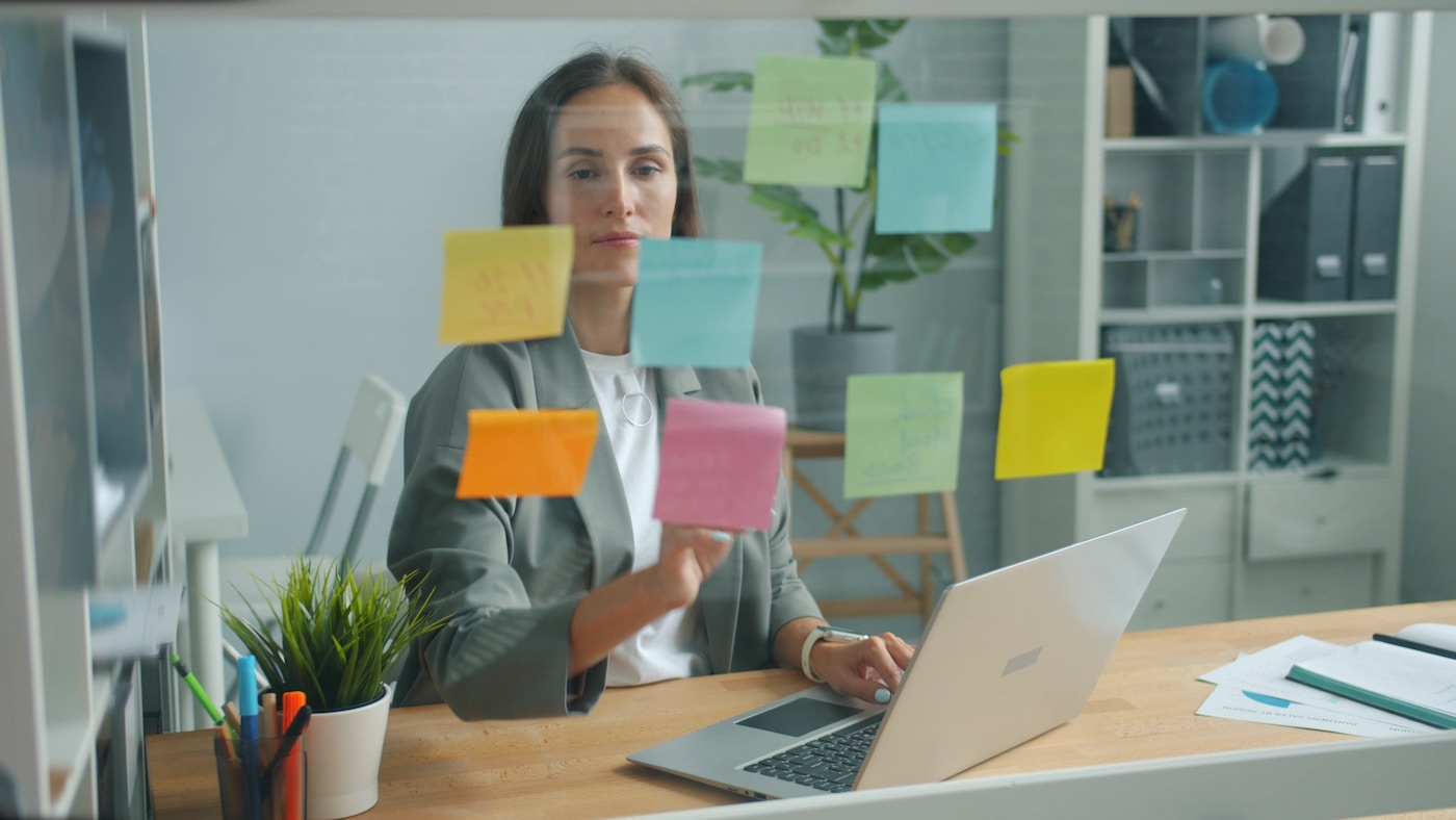 A person arranging sticky notes on a glass board