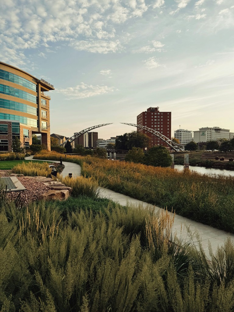 Curving path through grassy area towards a modern bridge.