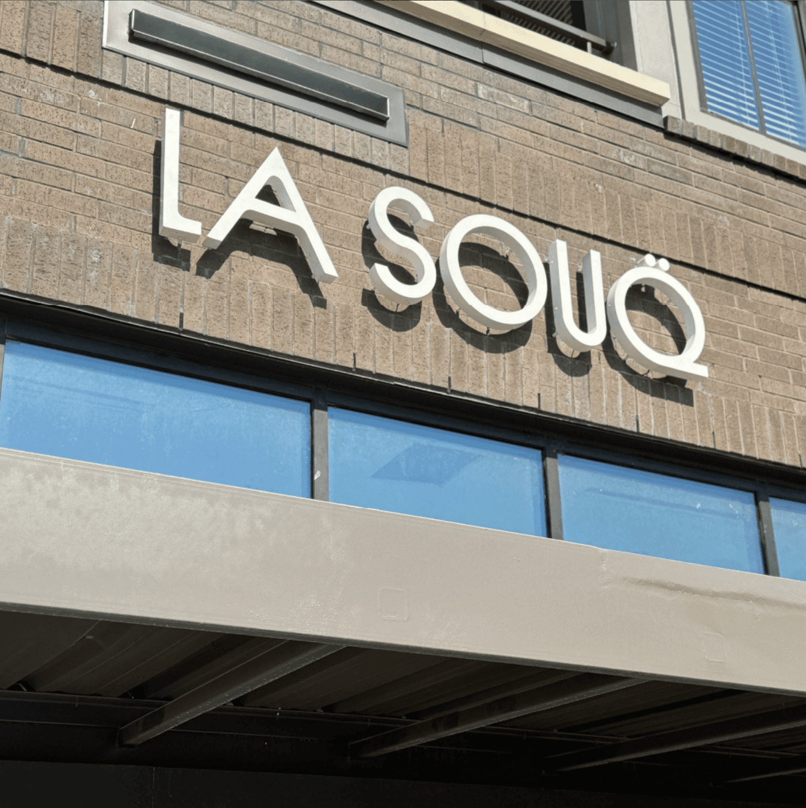 La Souq illuminated channel letter signage mounted on brick café storefront.