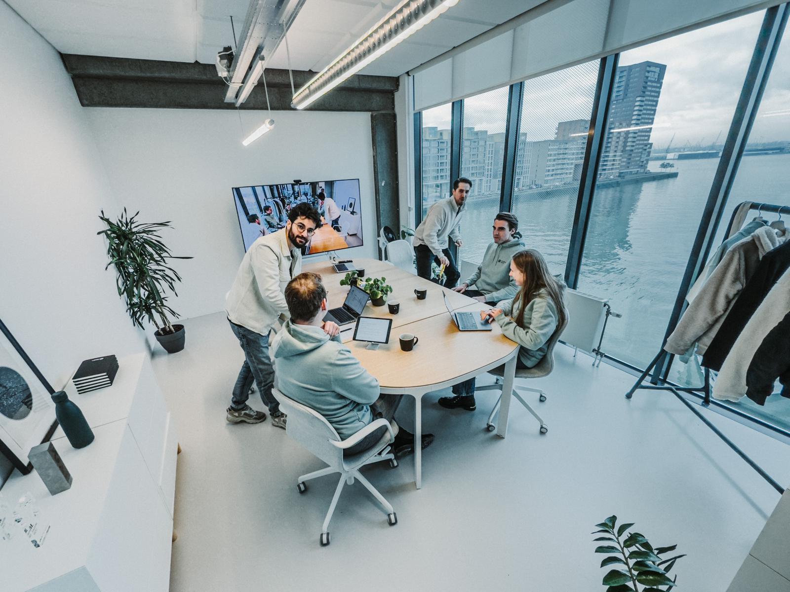 A group of five people in a modern office setting, engaged in a meeting