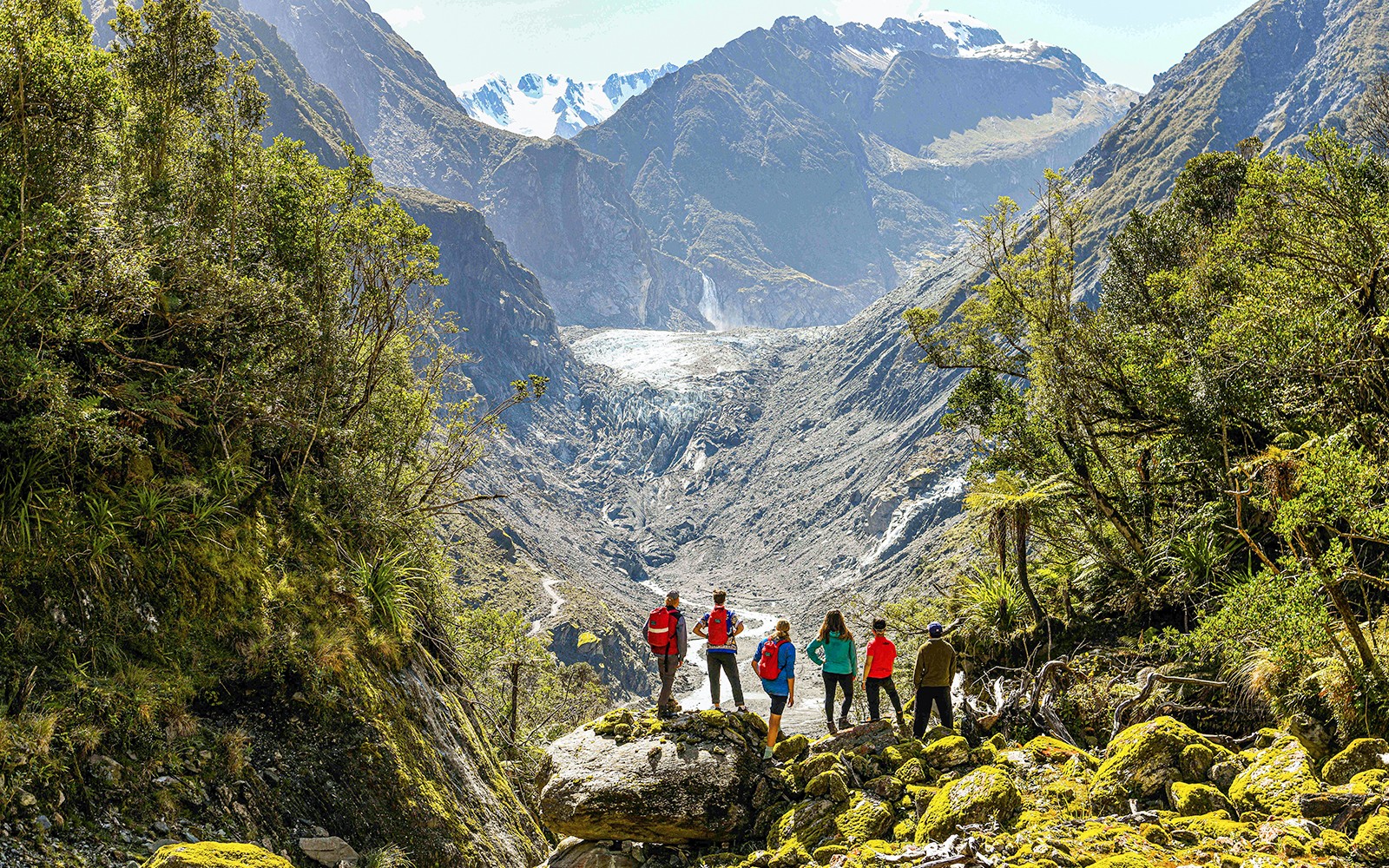Grupo de turistas visitando el Valle del Glaciar Fox en un recorrido guiado en bicicleta eléctrica y caminata.