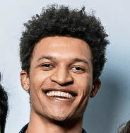 A smiling young man with dark curly hair and a joyful expression, embodying the positive spirit of PointOne's team and.