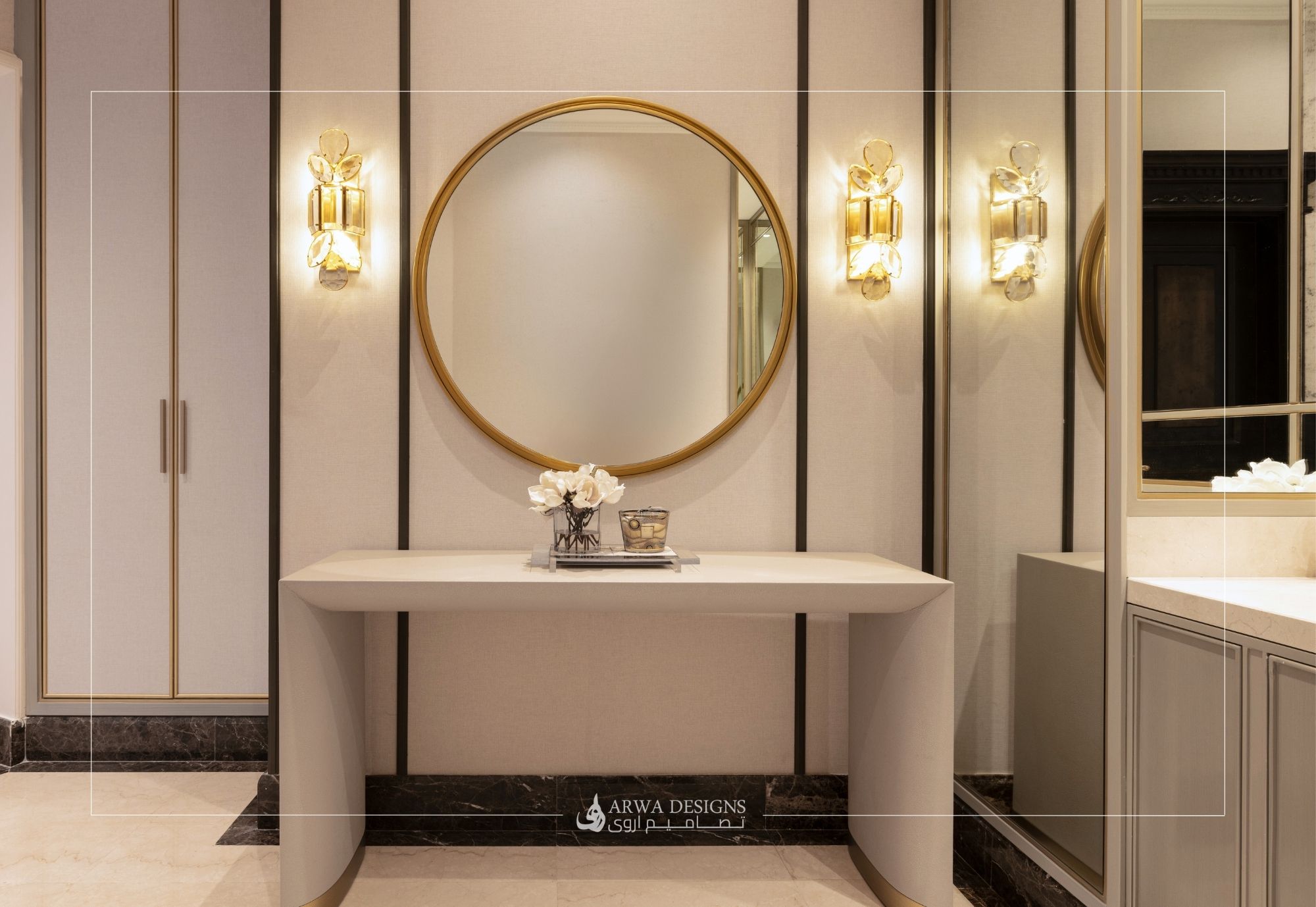 كونسول مدخل رمادي بتصميم عصري مع مرآة دائرية بإطار ذهبي وتكسيات جدارية سوداء وبيج.