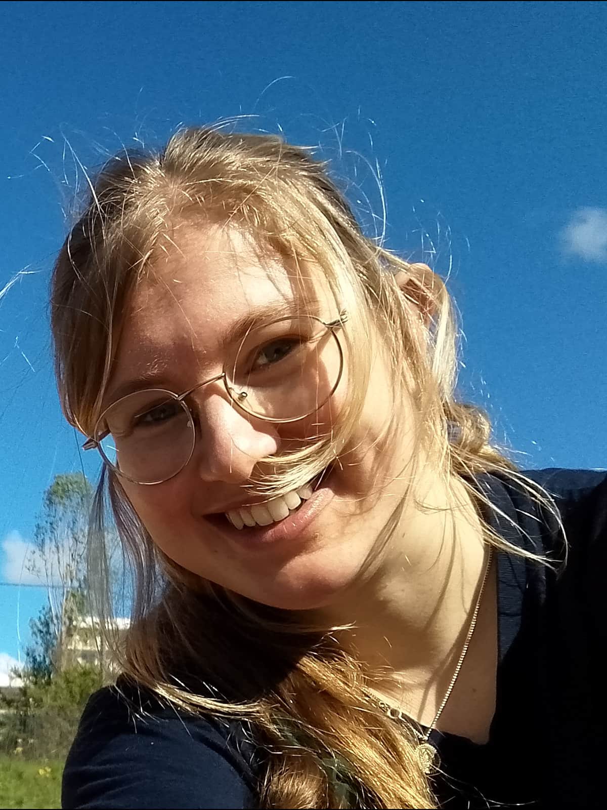 Portretfoto van Mila Bosch, lachend in een zonnige buitenomgeving.