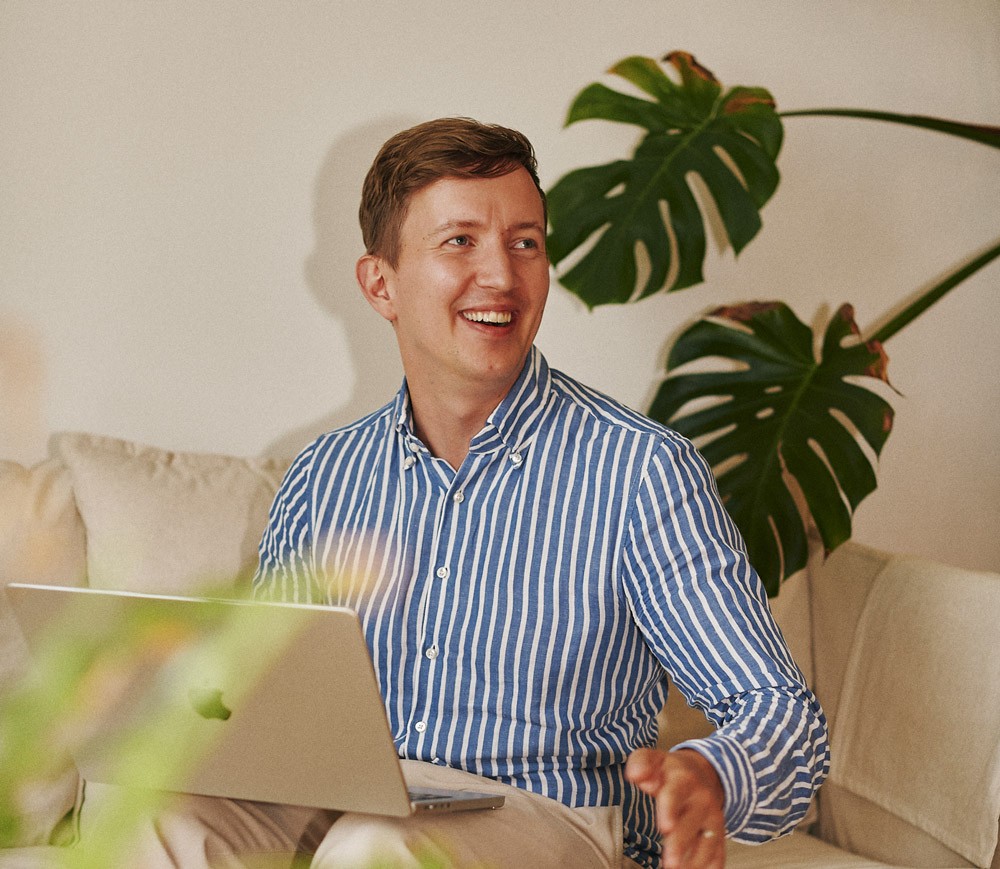 Heads' CEO Anton Fagerberg smiling on a couch with a laptop on his lap