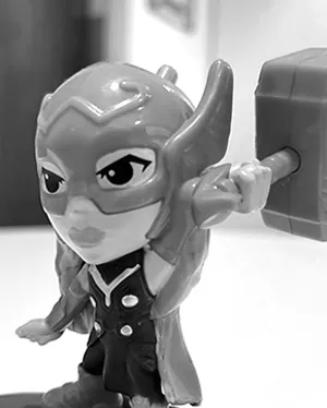 Professional headshot of a brunette woman in a white shirt, arms crossed, on a clean minimal background.