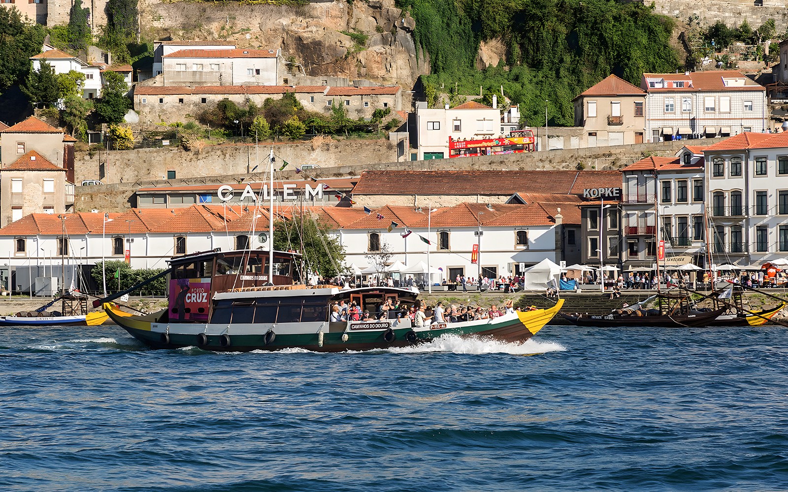 Hajókirándulás a Douro folyón, miközben Porto történelmi vízpartja szolgál háttérül.