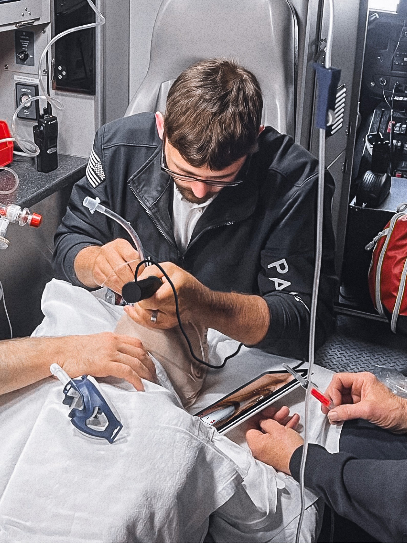 Paramedic intubating a patient in the back of an ambulance using the IntuBlade disposable video laryngoscope connected to a tablet.