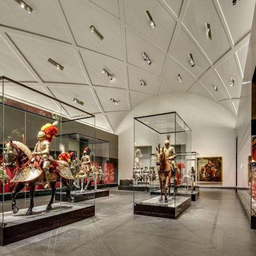 Museonäyttely, joka esittelee lasivitriineissä ratsujen haarniskoja holvikaarellisen, geometrisen katon alla.