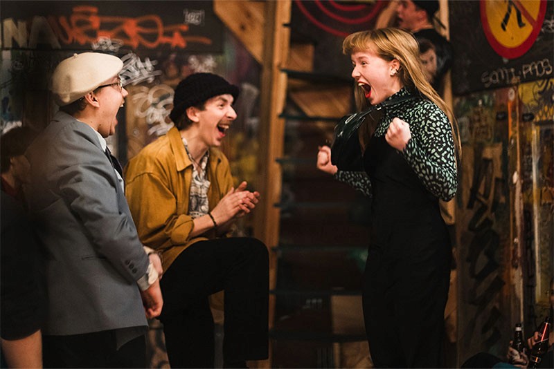 Karl Birnbaum (Silo) and Maria Helena Seppik (Nora) cheer with joy as Nora scores a basket in a lively bar scene from Rolling Papers (Pikad paberid)