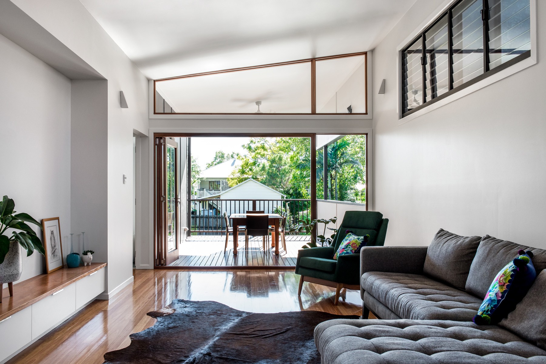 Rear living area at Oxford Cottage featuring high-level glazing, timber floors, and a relaxed lounge setting opening toward the garden.