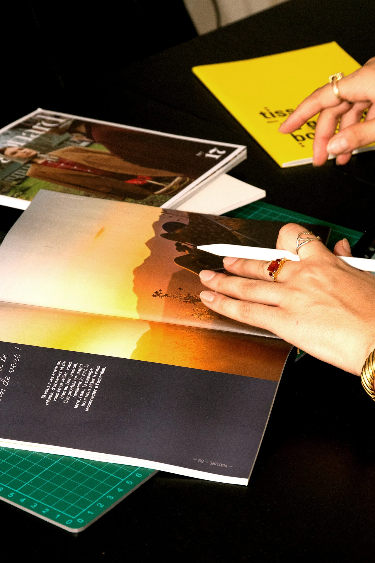 Graphiste annotant avec un stylet une revue photo pour concevoir un moodboard et une direction artistique.