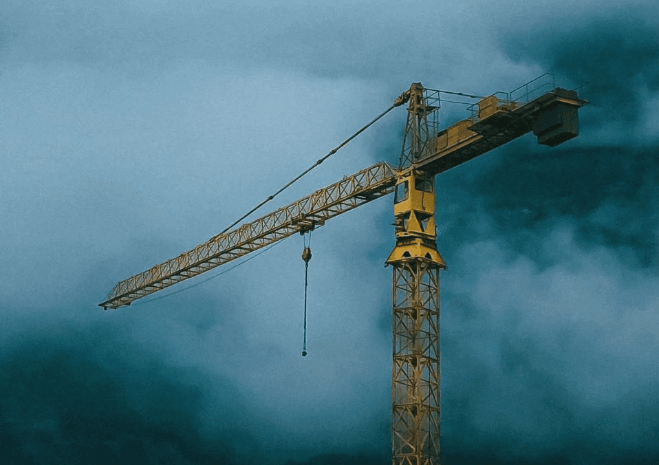 A yellow tower crane with a foggy mist backdrop