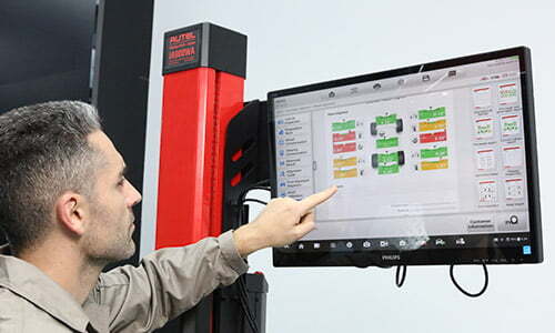 technician in an auto shop looking at a computer monitor