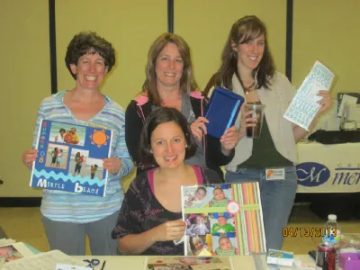 Four women showing off finished pages at a crop