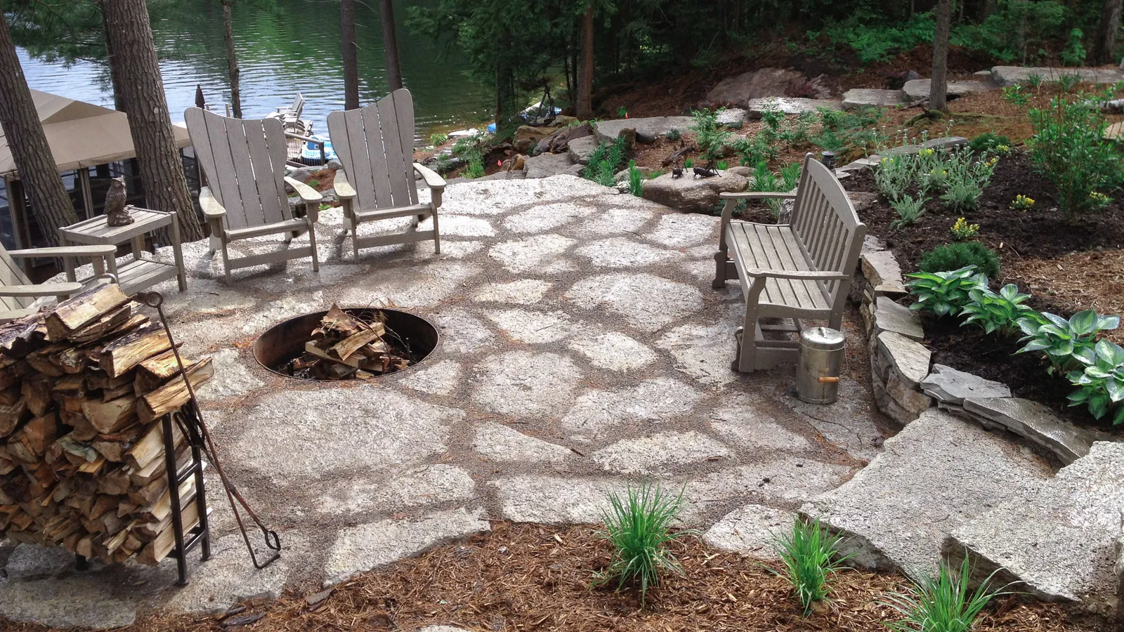 Split limestone patio with recessed firepit and muskoka chairs.