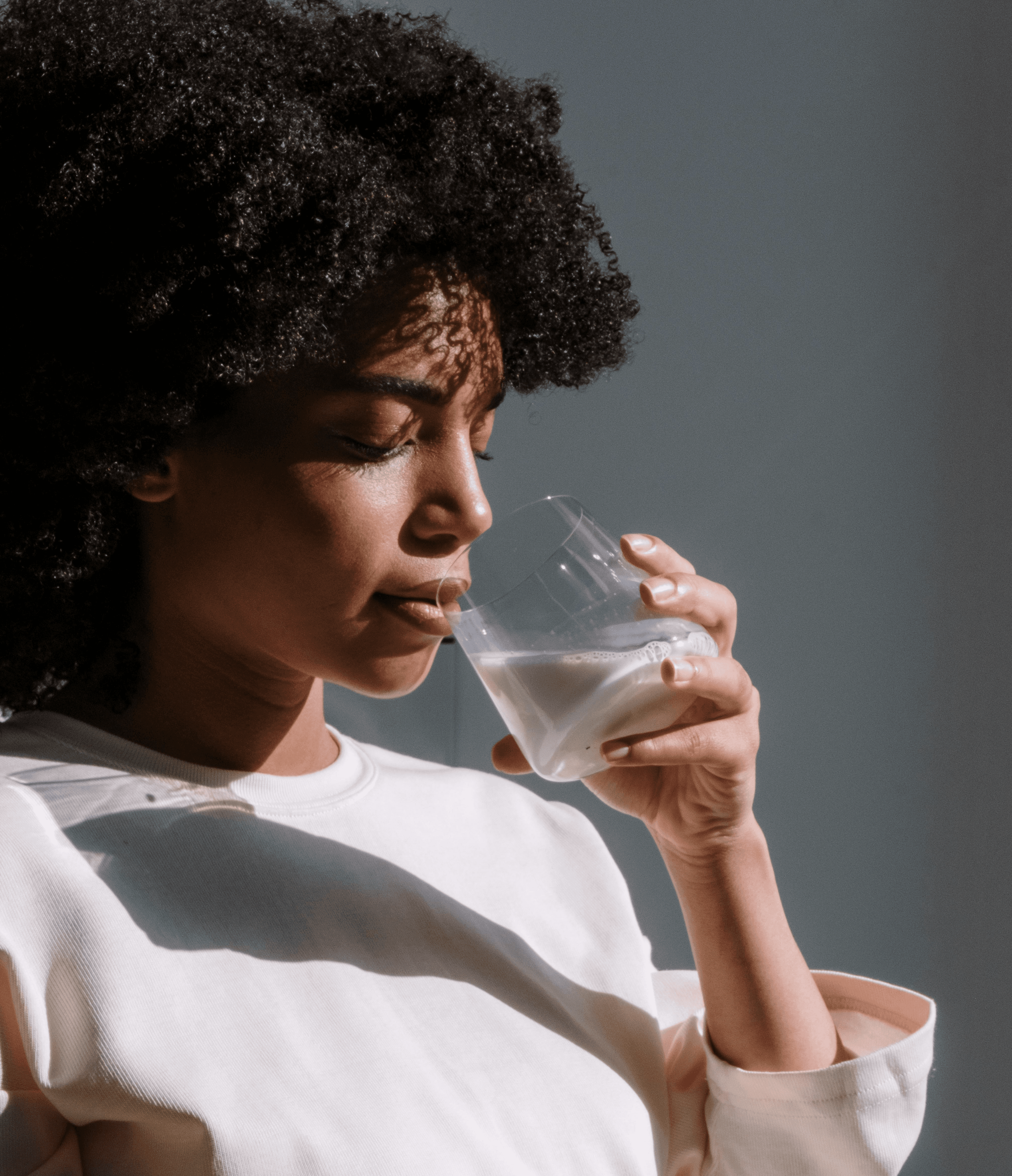 Calm woman drinking from a glass, symbolizing inner balance, rejuvenation, and cellular health supported by exosome and peptide therapy.