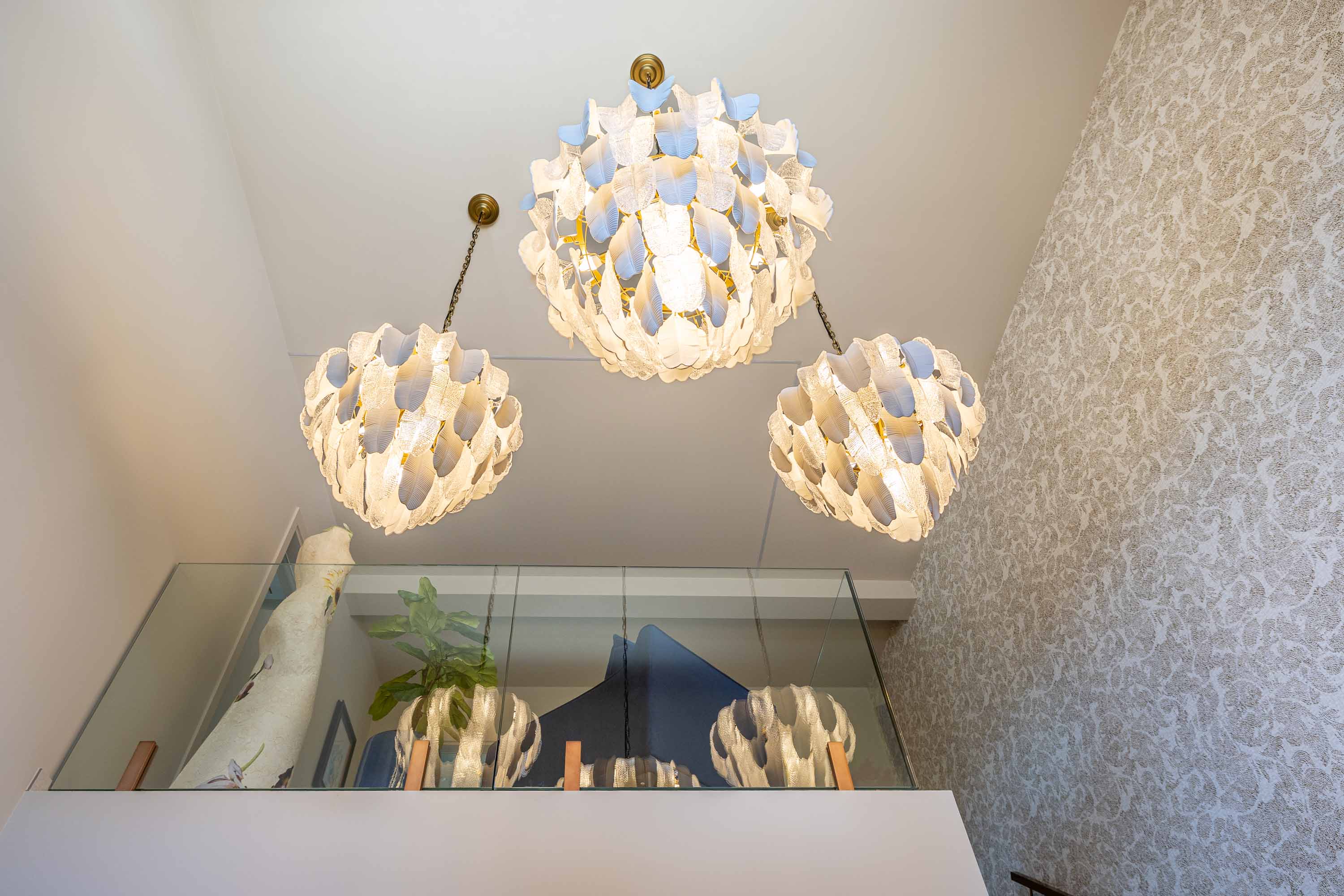 Cluster of white petal-glass chandeliers above a stairwell