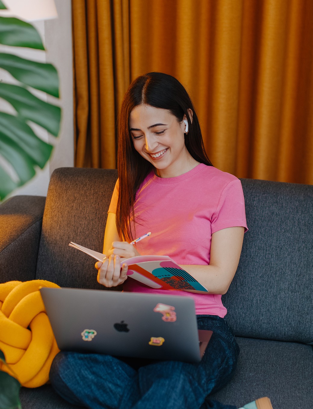 A woman sitting on the couch, having a video call and taking notes