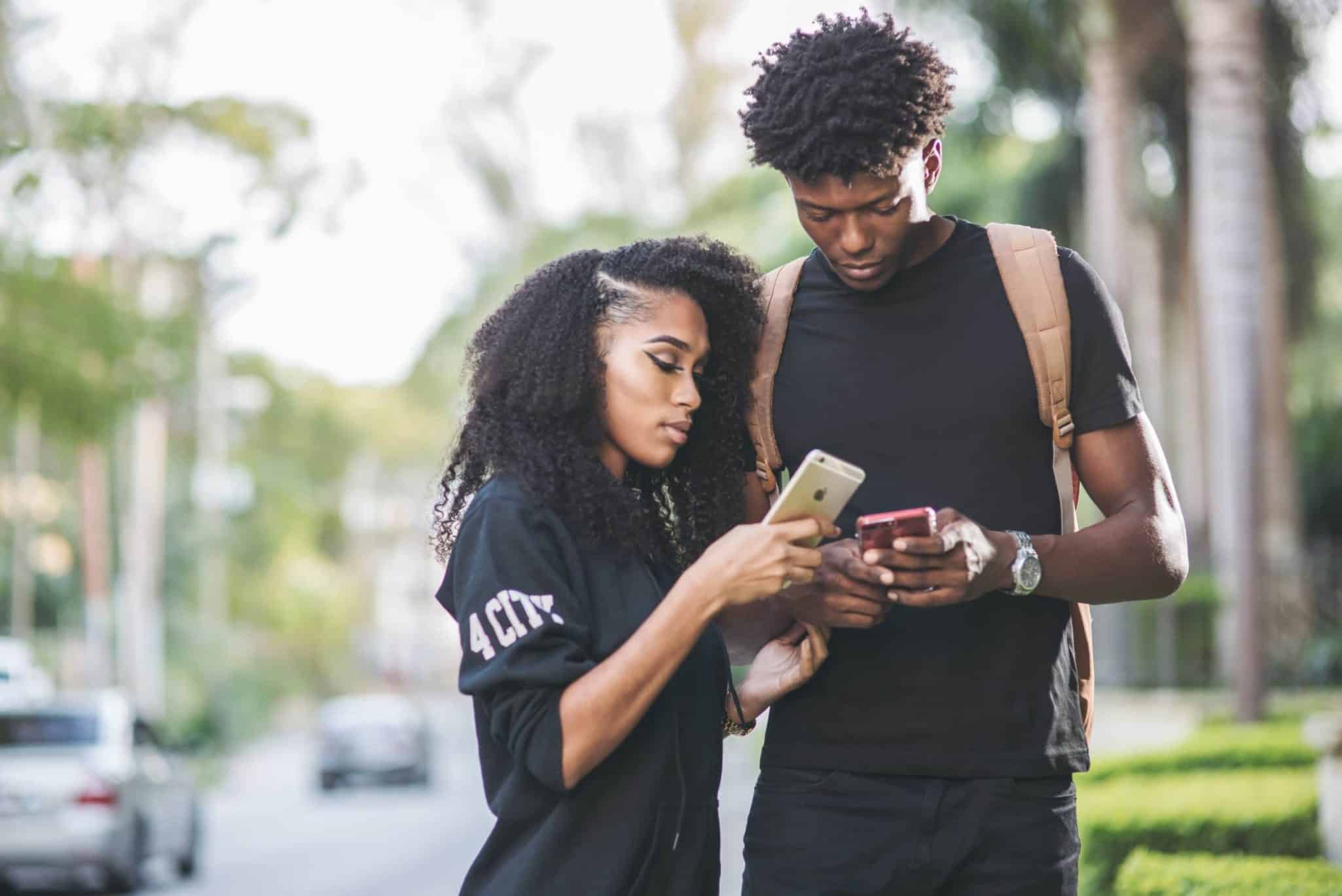 Young couple using smartphones outdoors, engaged in technology.