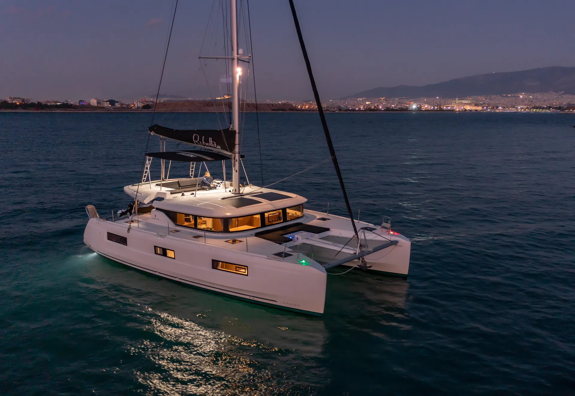 White Rock 36 speedboat with captain at helm cruising calm blue waters near Paros coastline with hills in background.
