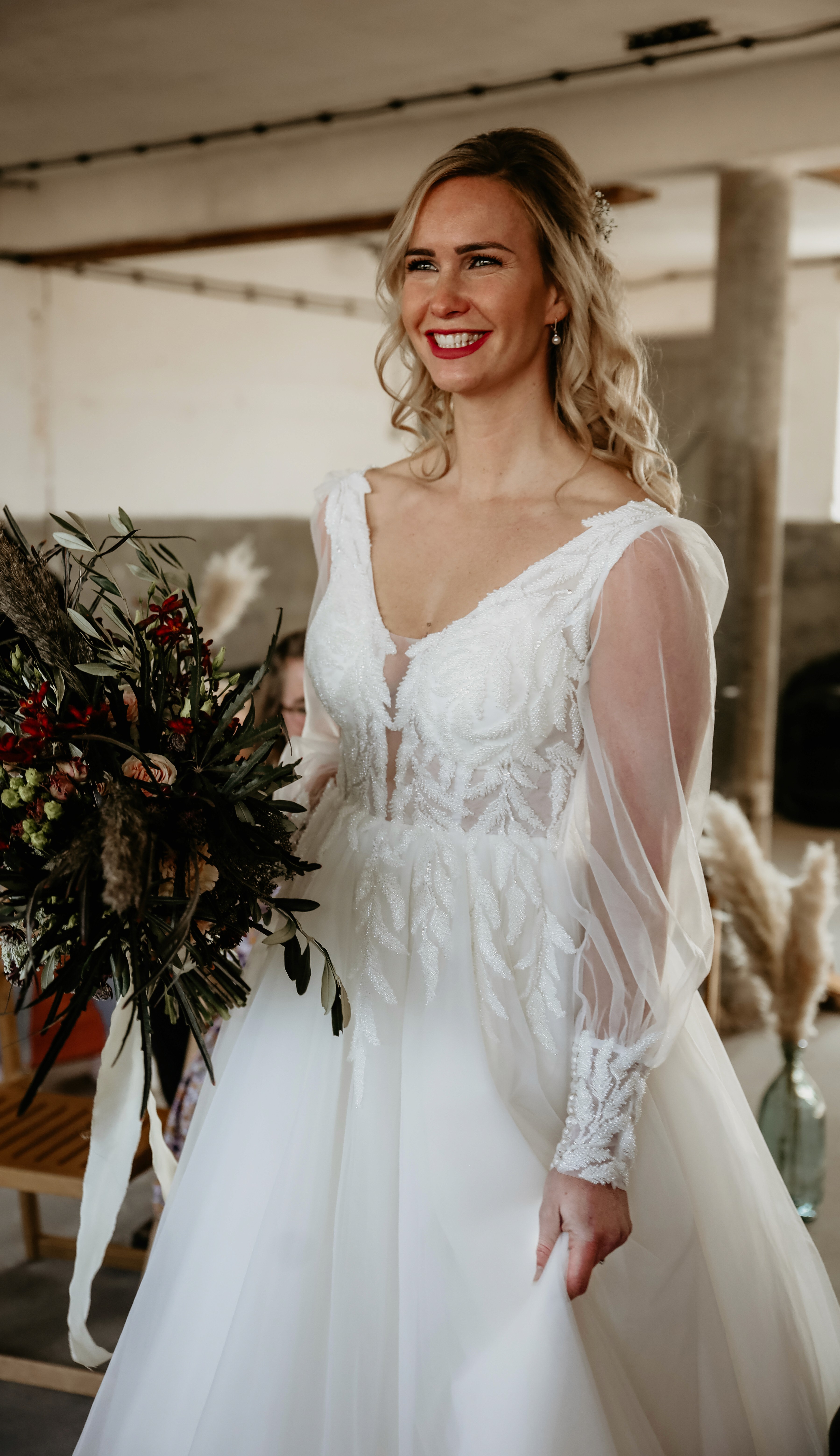 Verfijnde trouwjurk met kanten details en elegante sleep, gefotografeerd buiten bij een stijlvolle locatie – verkrijgbaar voor verhuur bij Magnolia Bruidsatelier in Deventer.