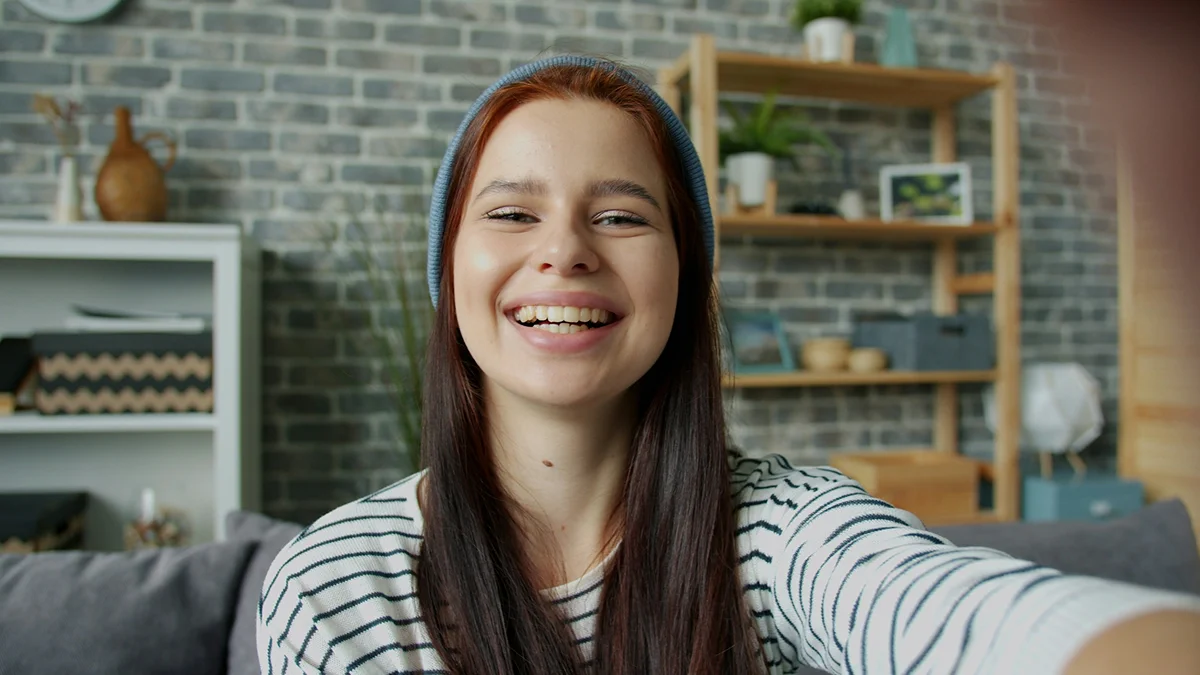 A smiling woman looking toward the camera at home.