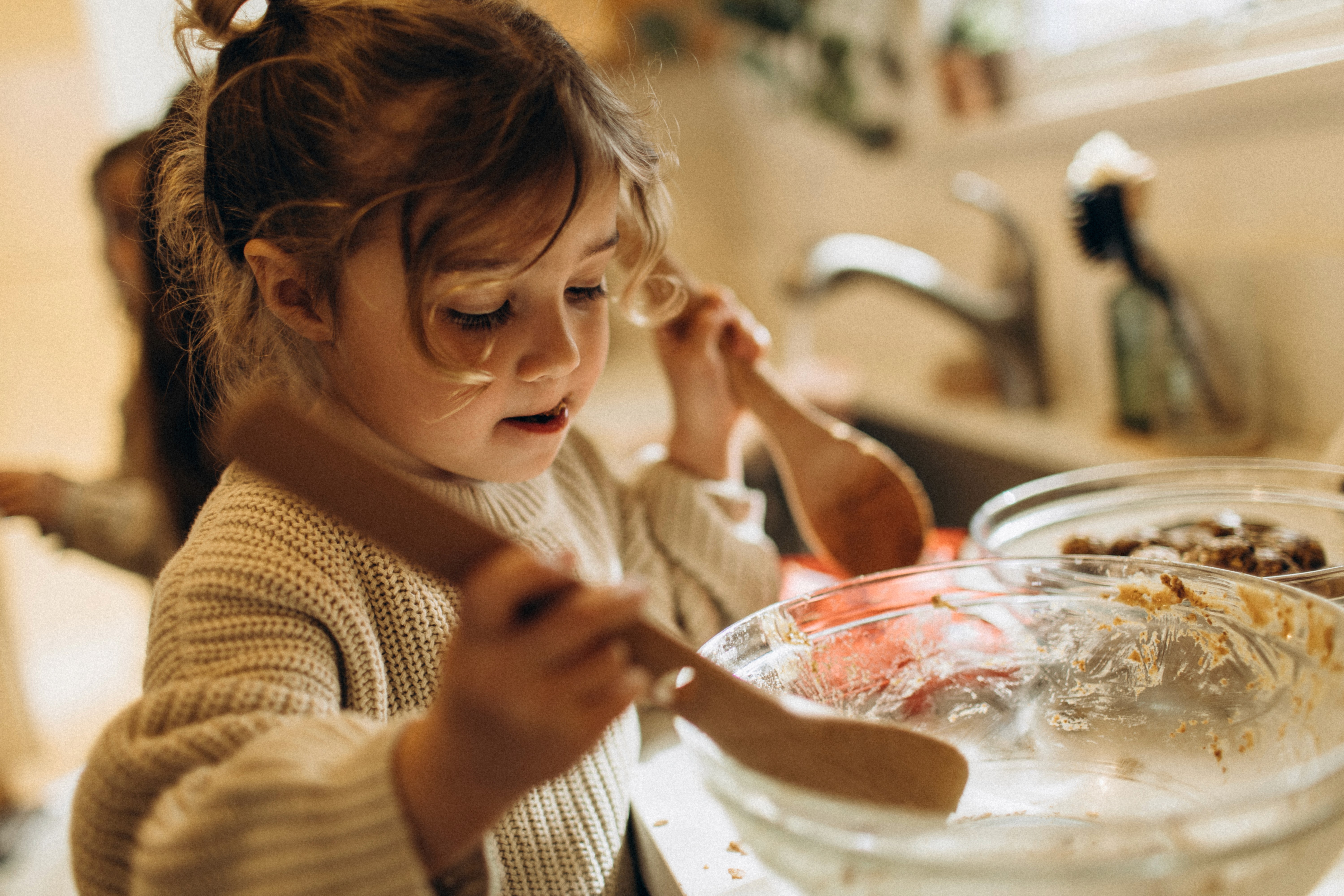 Kids mixing ingredients together during a natural, documentary-style family cooking moment.