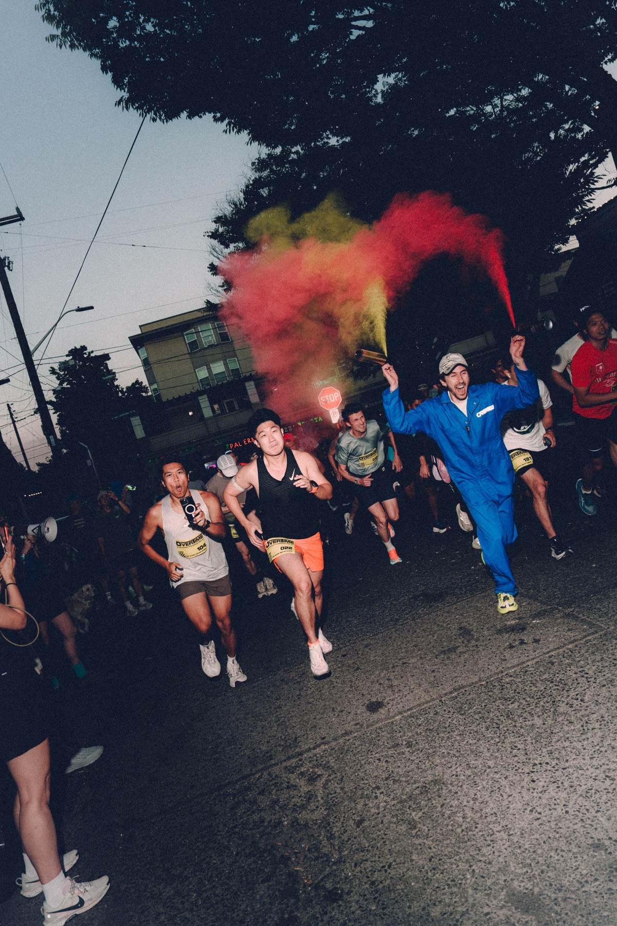 The start: runners break away under red and yellow smoke at dusk