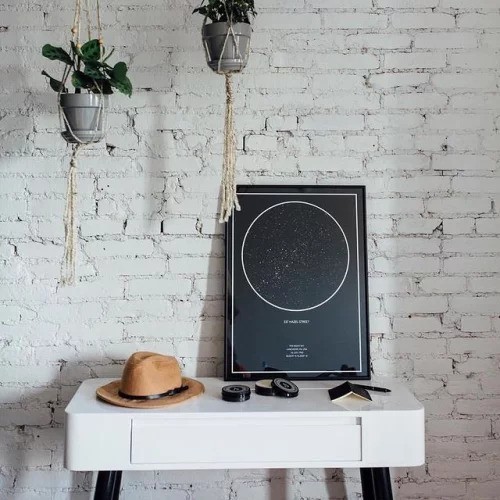 night sky star map print leaning against wall on desk