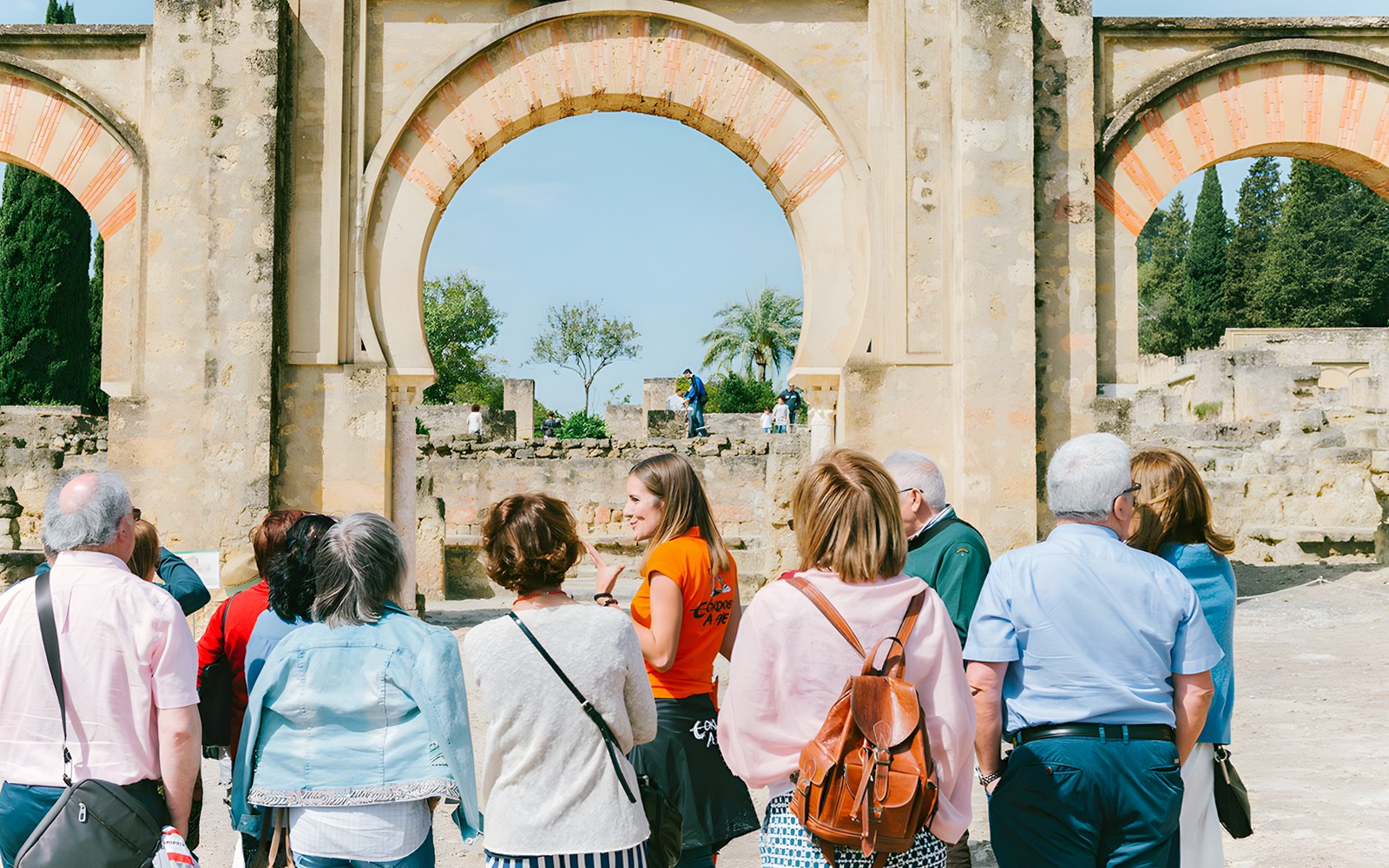 Geführte Gruppentour in Medina Azahara, Córdoba, mit historischen Bögen im Hintergrund.