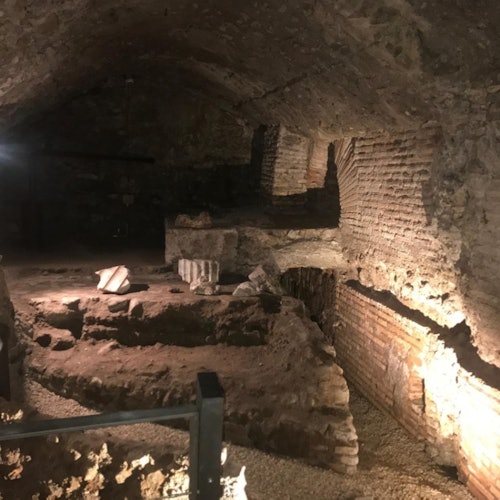 古老的地下废墟，砖墙和石块残骸，灯光昏暗，用聚光灯突出其粗糙的纹理。