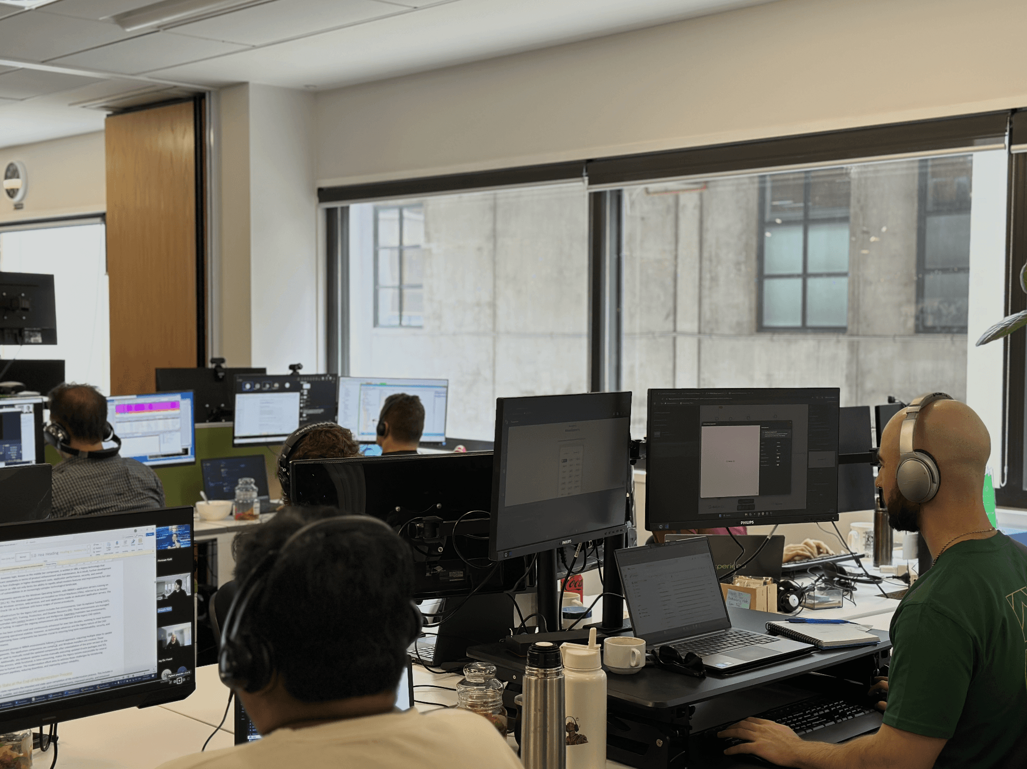 two men in a meeting in front of a big screen in an office