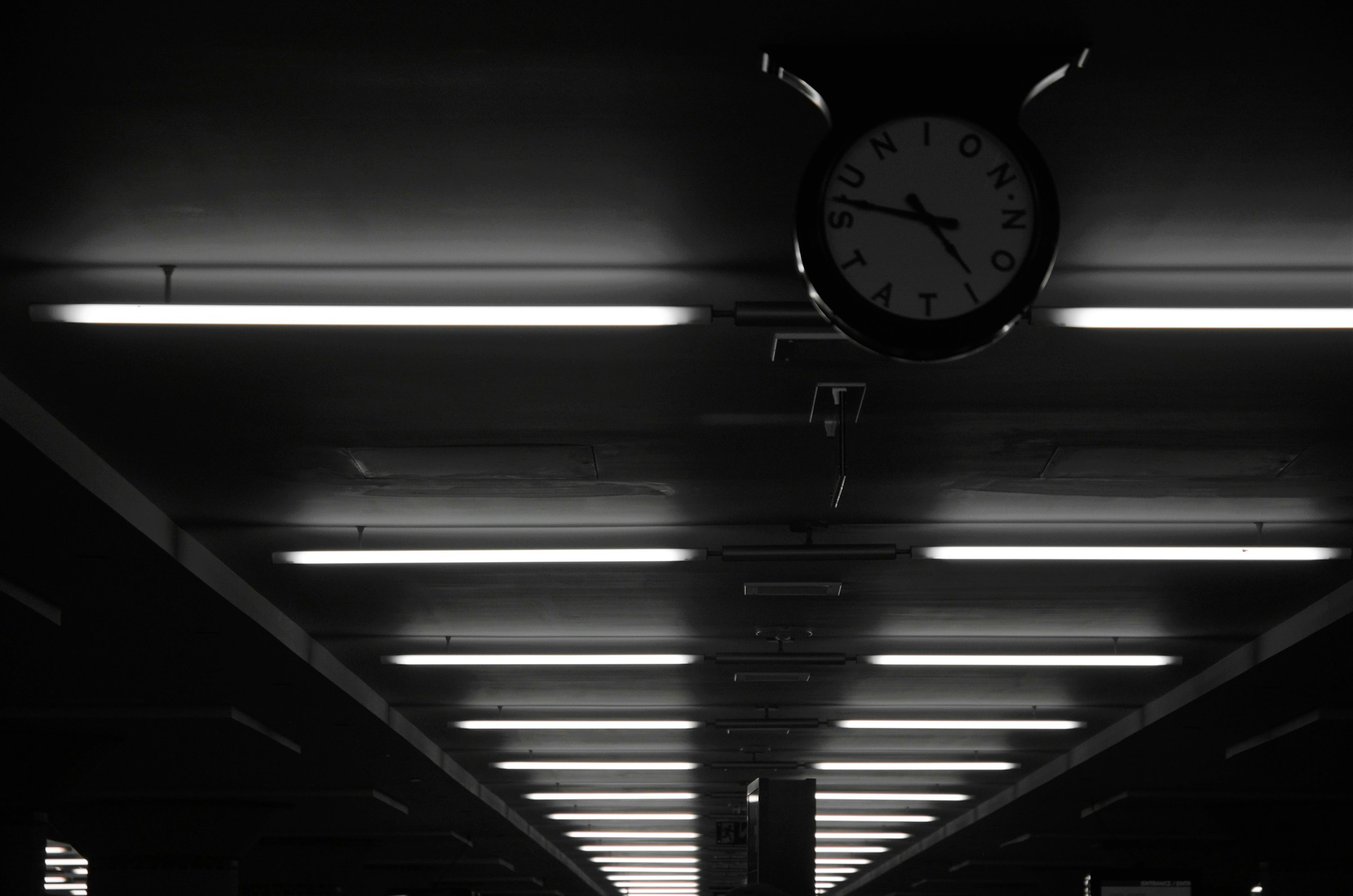 Tagwerk Rail, a black and white photo of a clock hanging from the ceiling