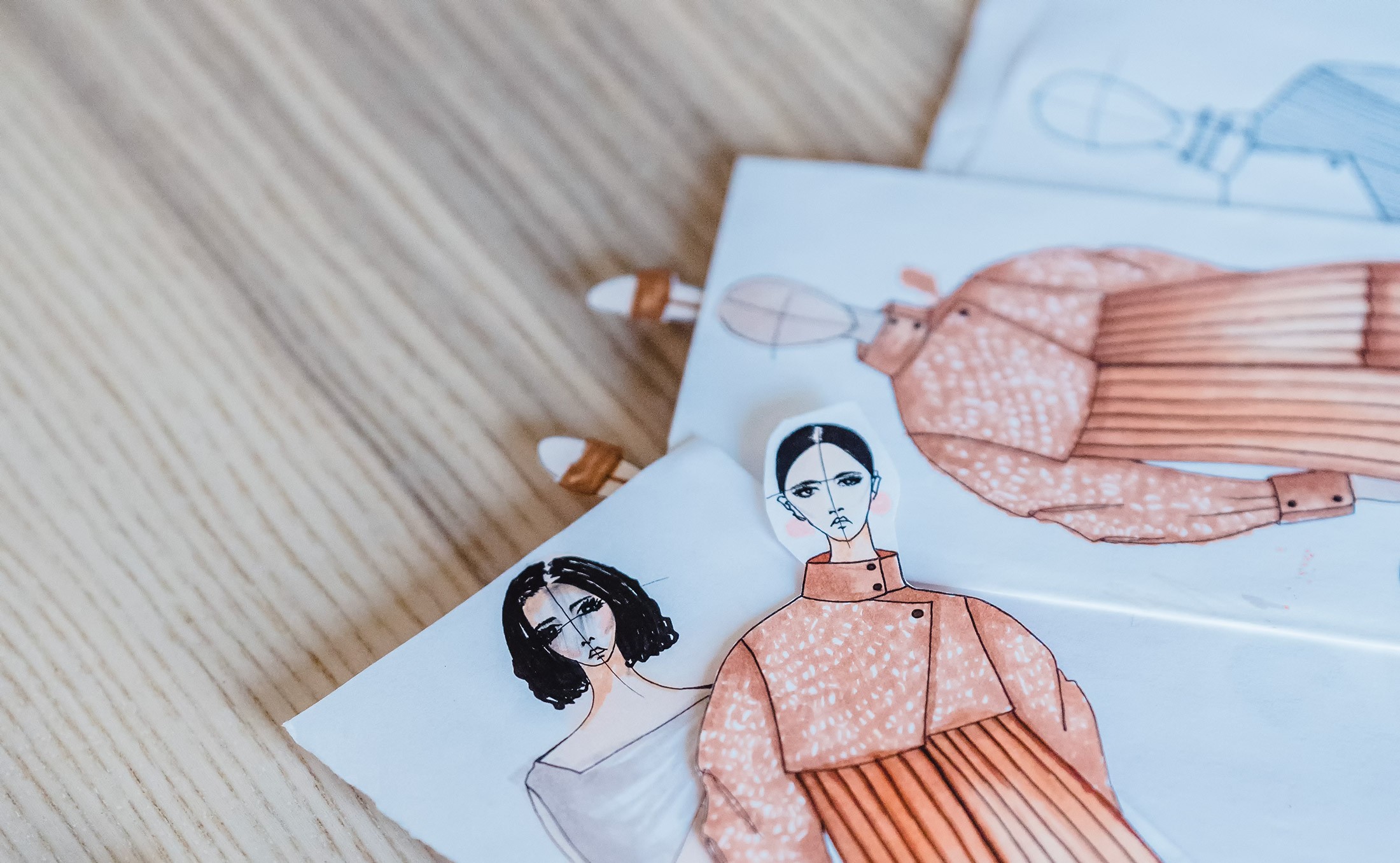 Paper fashion sketches on desk.