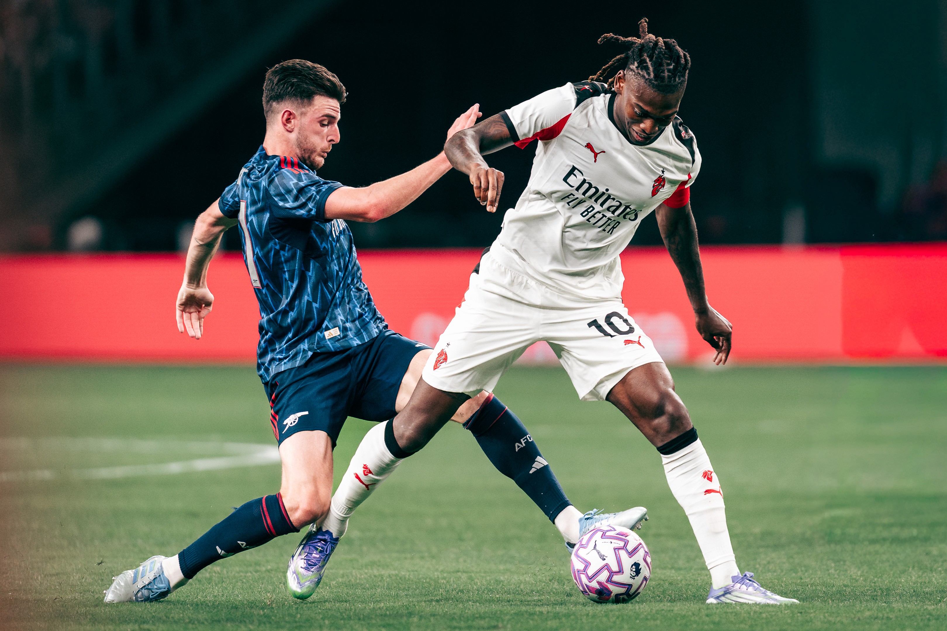 Declan Rice tussles with Rafael Leão for the ball during a match between Arsenal and A.C. Milan at the National Stadium in Singapore for the Singapore Festival of Football 2025