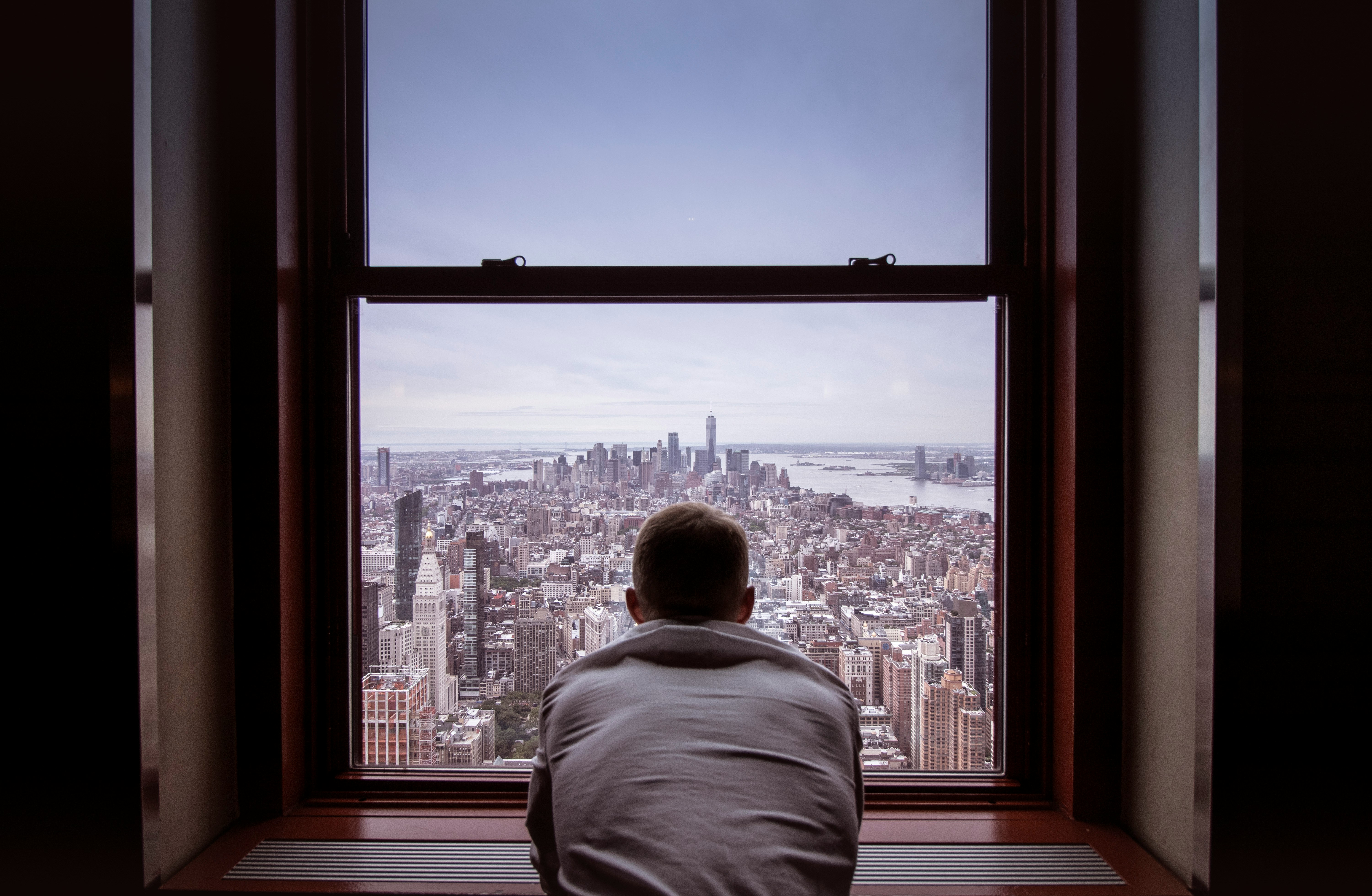 A Person looking out of the Window on New York City, symbolizibng an Account Manager that is benefitting from an AI Email assistant