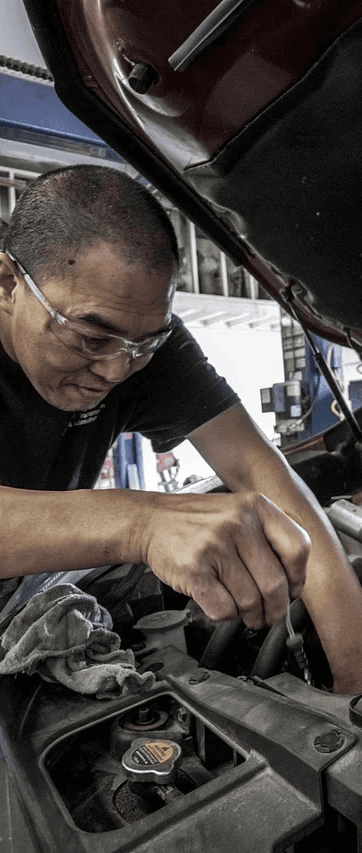 A mechanic works on a car engine.